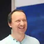 Homme souriant avec un fond bleu.