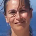 Portrait d'une femme souriante, mer en arrière-plan.